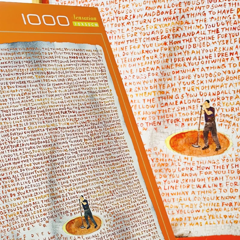 Close-up of Yellow puzzle and box with handwritten song lyrics in red and orange