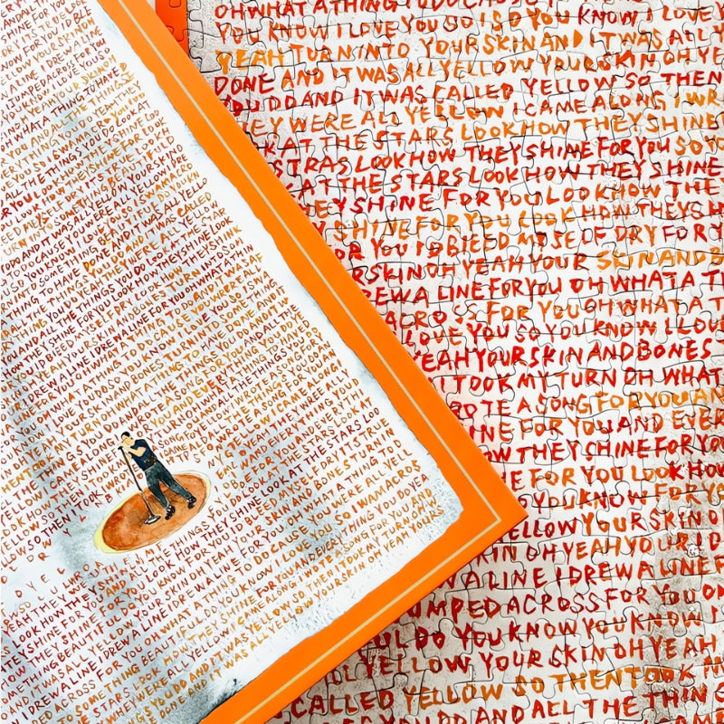 Close-up of Yellow puzzle and box with handwritten song lyrics in red and orange