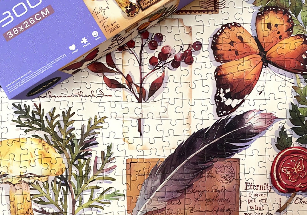 Close-up of assembled puzzle showing orange butterfly, feather, mushroom, and vintage letter details.