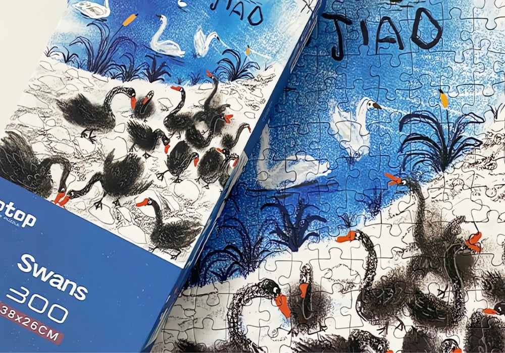 Partially completed puzzle showing swans by a pond next to the Swans puzzle box.