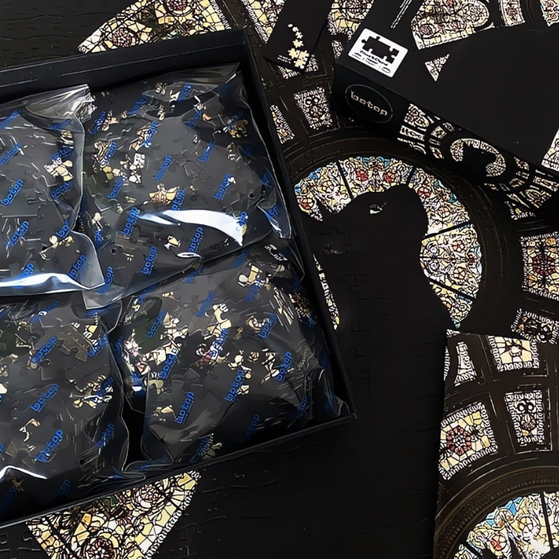 Open puzzle box with sorted bags and a partially completed stained glass cat puzzle underneath