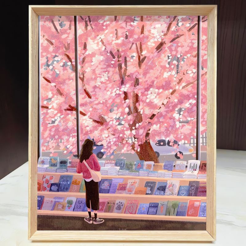 Framed Spring Bookstore puzzle showing girl browsing books beside cherry blossom tree