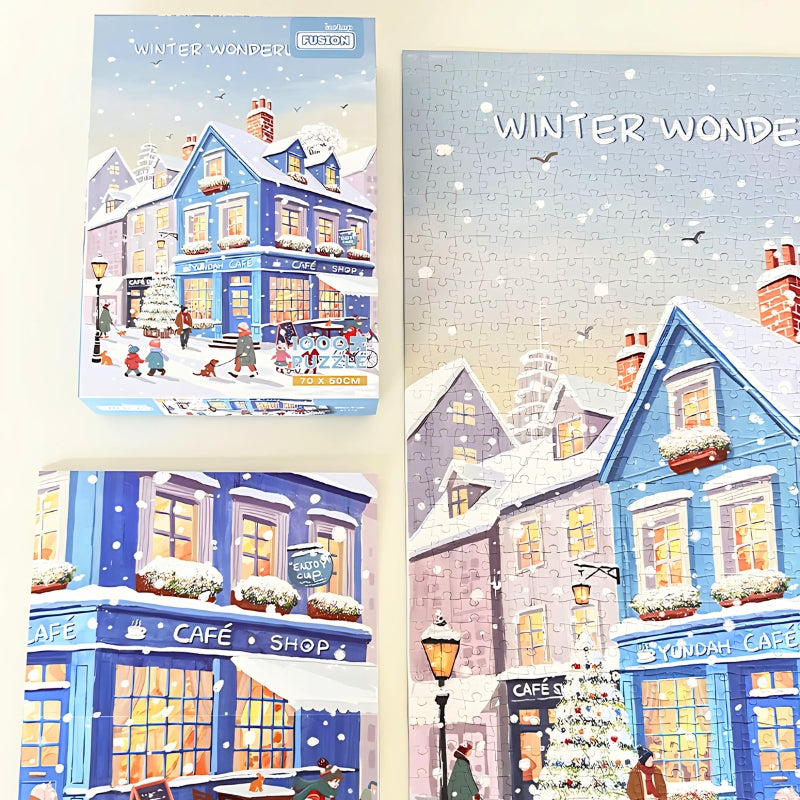 Flat lay of the puzzle box and completed Blue Cafe puzzle showing bright windows and snowy rooftops.