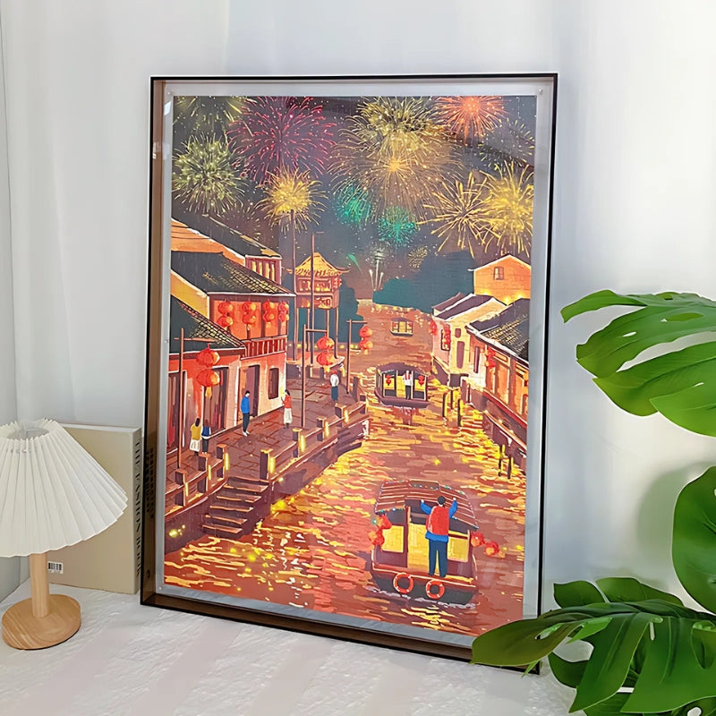 Framed display of completed “The Water Town Under Fireworks” puzzle with fireworks, boats, and traditional town buildings.