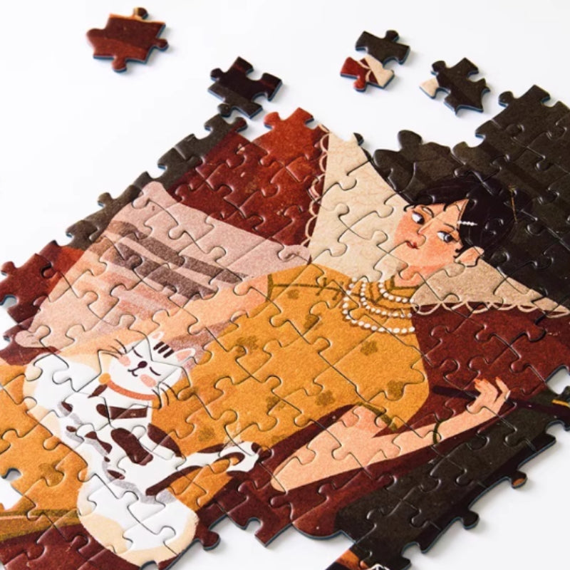 Close-up of partially completed jigsaw puzzle showing a woman in a mustard dress holding a white cat.