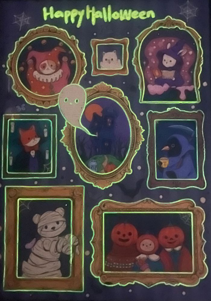Glow-in-the-dark view of the completed puzzle showing illuminated green outlines of the frames, ghost, and “Happy Halloween” text.