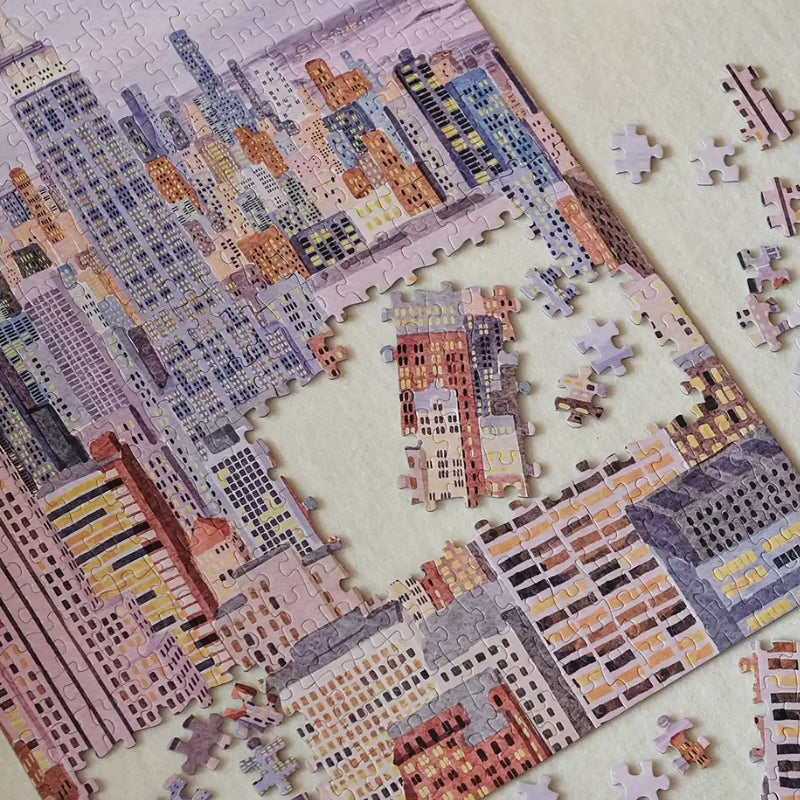 Close-up of partially assembled Fantasy Manhattan puzzle showing interlocked pastel city-scape pieces.