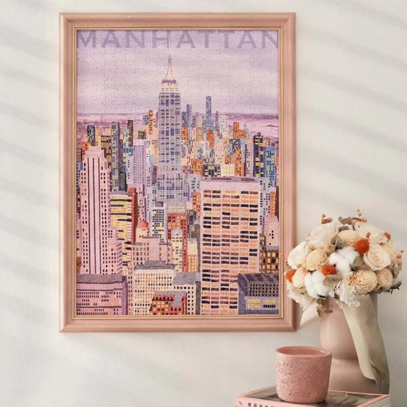 Completed Fantasy Manhattan jigsaw puzzle framed on a wall beside a vase of flowers.