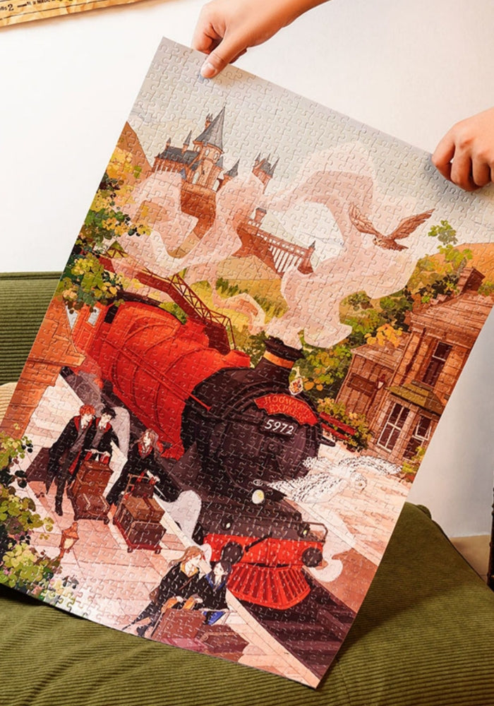 The fully assembled puzzle being held upright, showing the complete train scene with Hogwarts in the background.