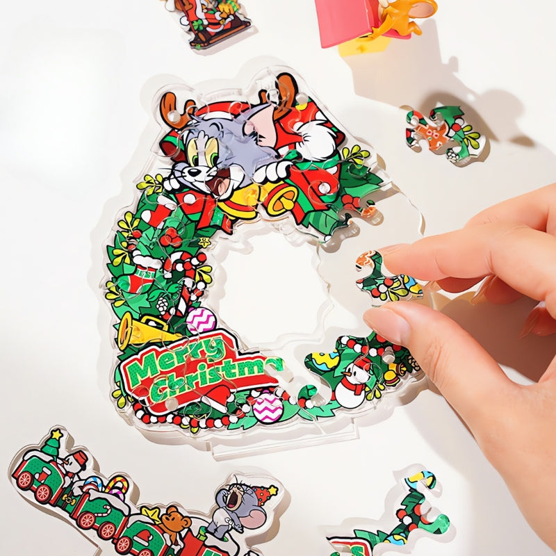 Hand placing a puzzle piece into the Tom and Jerry Christmas Swing Wreath acrylic puzzle on a white background.