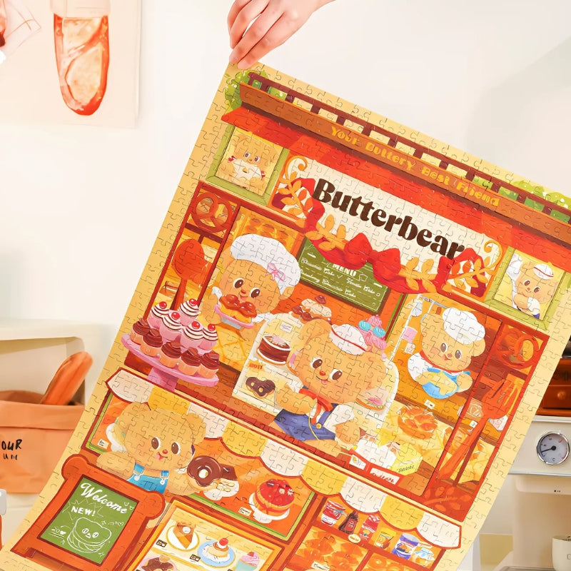 Person holding up the fully completed Butterbear – Dessert Paradise puzzle featuring a full bakery storefront.