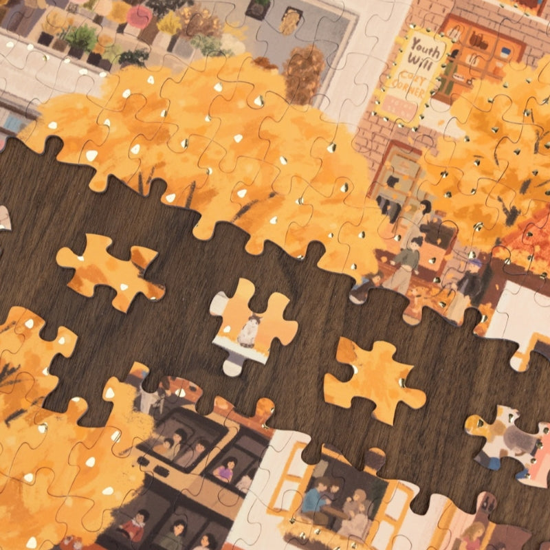 Puzzle pieces scattered on a table with sections of golden leaves.