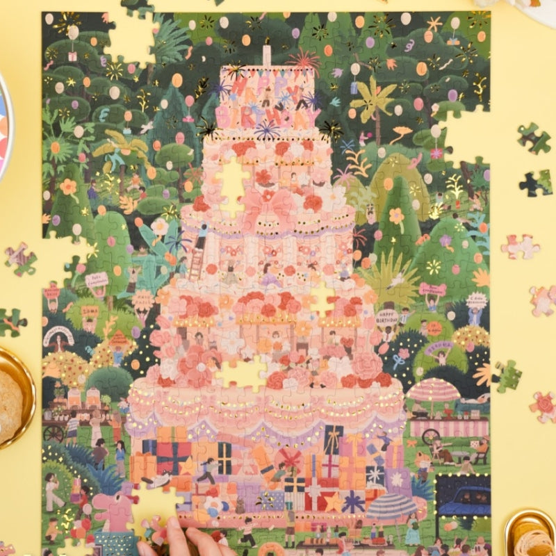 Puzzle detail with foil fireworks and “Happy Birthday” lettering on cake.