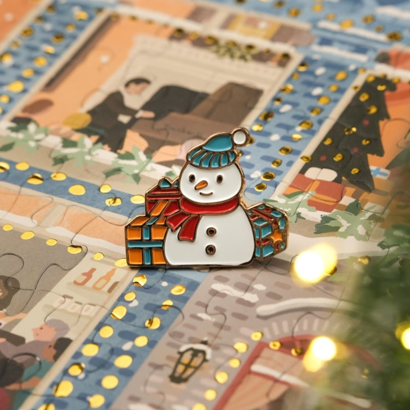 Close-up of a snowman enamel pin placed on top of puzzle artwork.