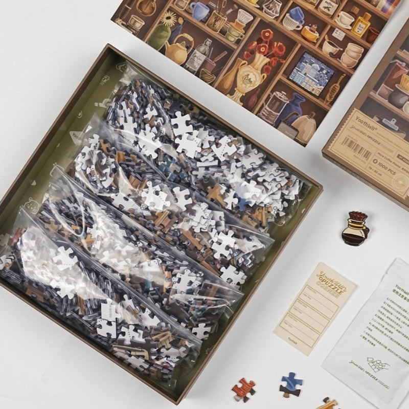 Open box with sealed puzzle bags, enamel pin, and puzzle glue packet.