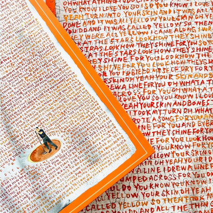 Close-up of Yellow puzzle and box with handwritten song lyrics in red and orange