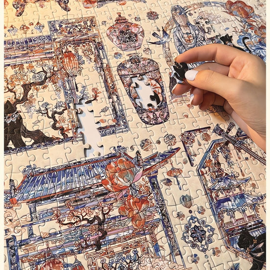 Close-up of hand assembling Yuan Dynasty puzzle with intricate blue and red line art of ancient scenes and temples