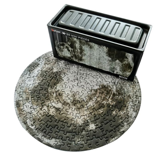 Round moon surface mini puzzle beside Botop black metal box.