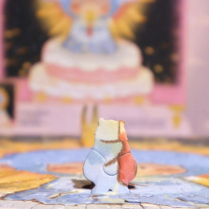 Close-up of a uniquely shaped bear puzzle piece standing upright on the assembled jigsaw surface with blurred artwork in the background.