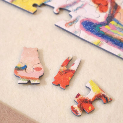 Three unique puzzle pieces — bunny ears, standard piece, and bear — displayed on a felt mat near the puzzle edge.
