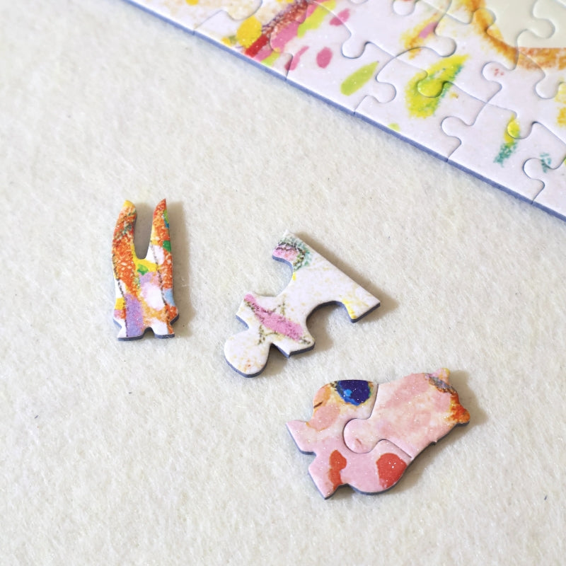 Three special-shaped puzzle pieces — bunny ears, standard piece, and bear — placed on a felt mat near the puzzle edge.