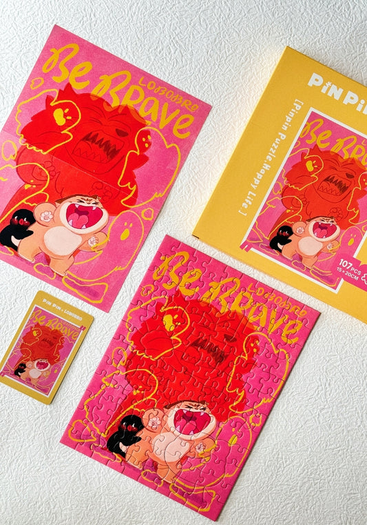 Flat lay of puzzle pieces, box, and art card from the Be Brave Lobobro mini puzzle.