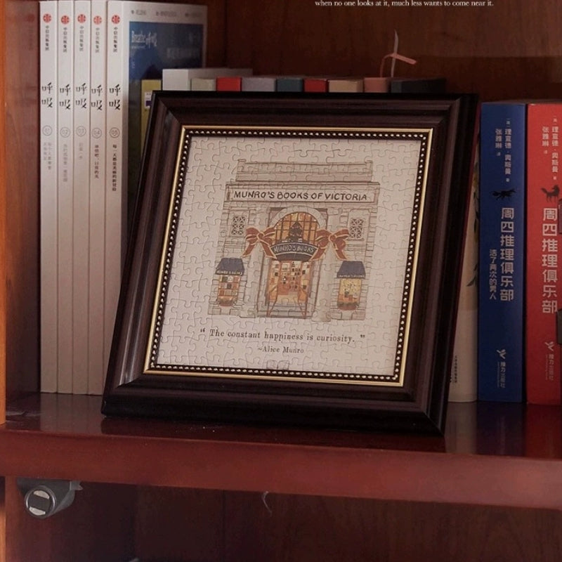 Framed Munro’s Books of Victoria mini puzzle displayed on a bookshelf with books around it.