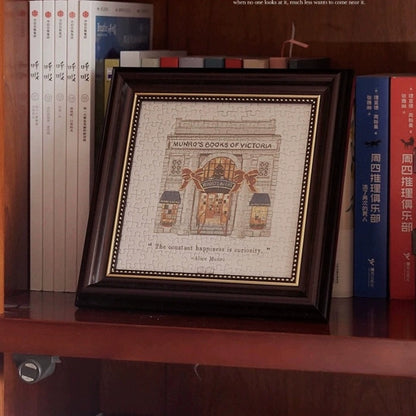 Framed Munro’s Books of Victoria mini puzzle displayed on a bookshelf with books around it.