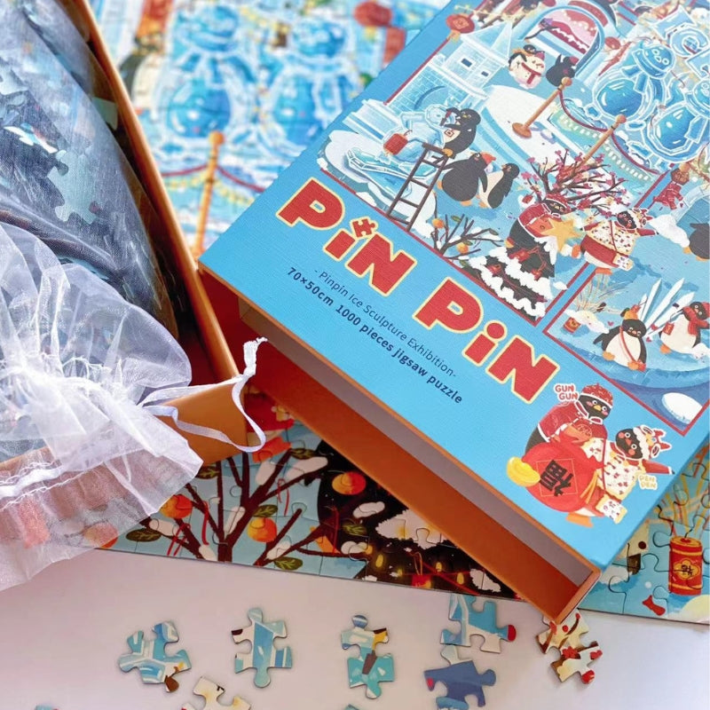 Open Pinpin Ice Sculpture Exhibition puzzle box with 1000 pieces in a mesh bag and colorful artwork beneath.