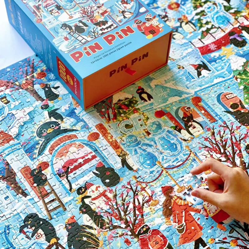 Hands assembling Pinpin Ice Sculpture Exhibition puzzle with detailed winter festival scene and penguins.