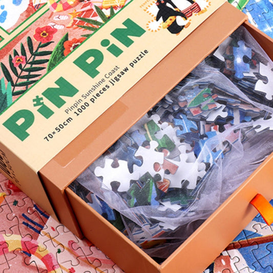 Pinpin Sunshine Coast jigsaw puzzle box opened to show 1000 colorful puzzle pieces packed in a mesh bag.
