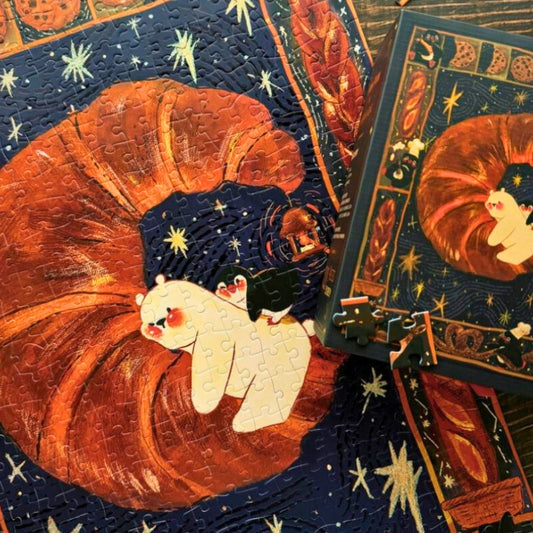 Sweet Dream puzzle in progress showing croissant artwork with playful penguins and a bear, next to the box.