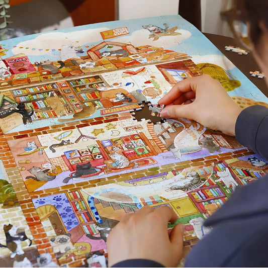 Puzzle being assembled on a table showing detailed cat scenes