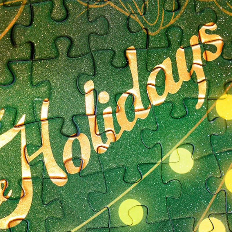 Close-up of green puzzle piece from Christmas Memoirs with the word “Holidays” in gold foil.
