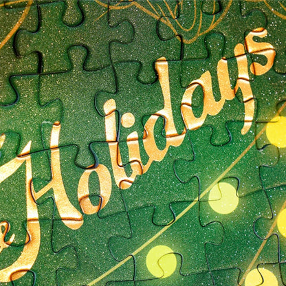 Close-up of green puzzle piece from Christmas Memoirs with the word “Holidays” in gold foil.