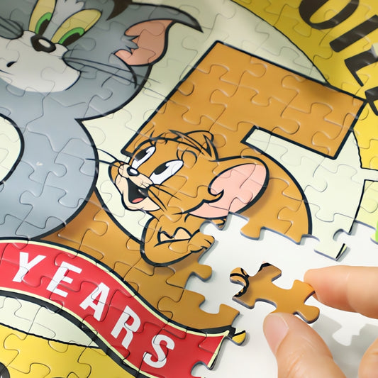 Close-up of puzzle showing Tom and Jerry with a “75 Years” banner and a hand placing a piece.