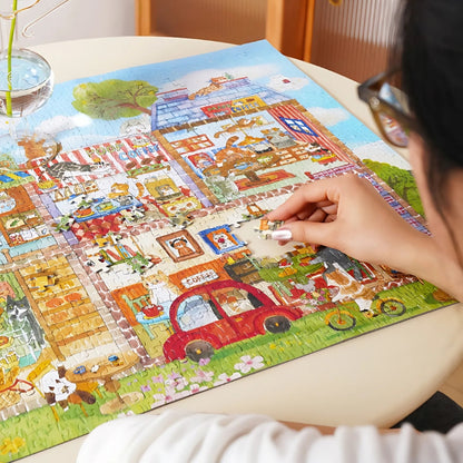 Person assembling the Café Paws & Whiskers puzzle on a round table.