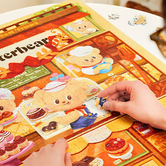 Hands placing puzzle pieces in Butterbear – Dessert Paradise puzzle showing the central cake display window.