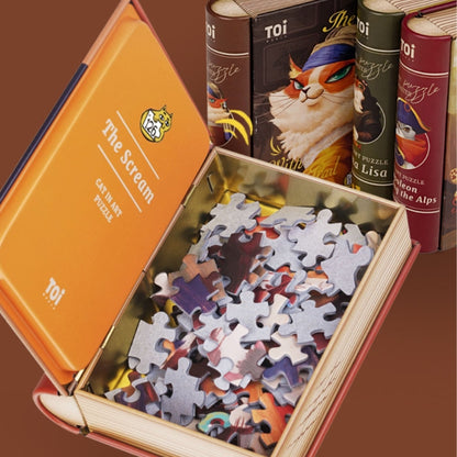 Open book-style box for The Scream cat art puzzle by TOI, showing puzzle pieces inside.