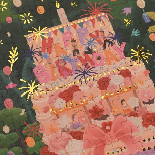 Partially completed Birthday Party puzzle featuring a tall pink layered cake with festive background.