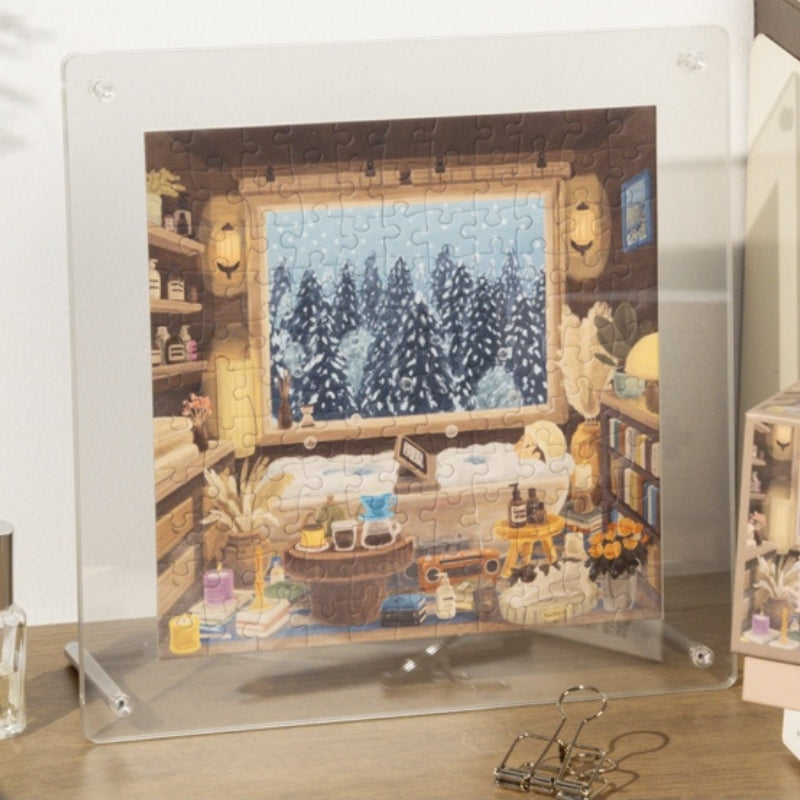 Completed Snowy Cabin mini puzzle displayed in a clear acrylic frame.